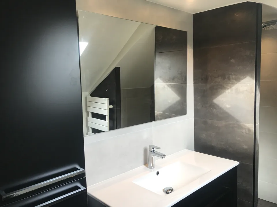 Meuble vasque noir et miroir sous la pente du toit