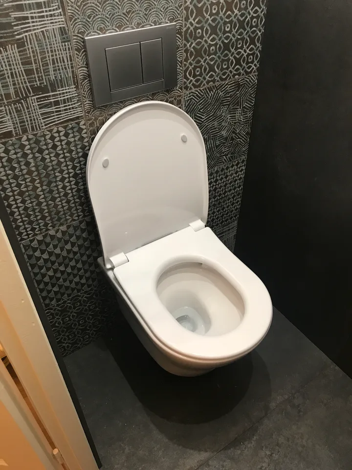WC suspendu devant une faïence à motifs gris